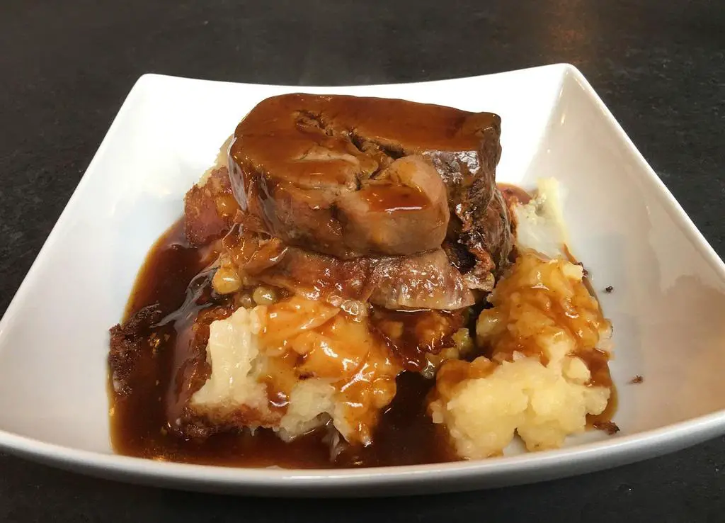 Slow Baked Beef Brisket Placed on a Bed of Potato Mash and Covered With Gravy