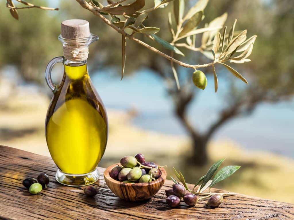 olive oil and berries are on wooden table