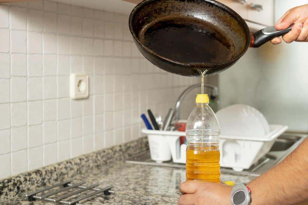 placing recycled edible oil-from-a-frying pan into a plastic bottle
