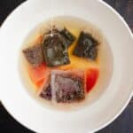 steeping herbal tea bags in a white bowl