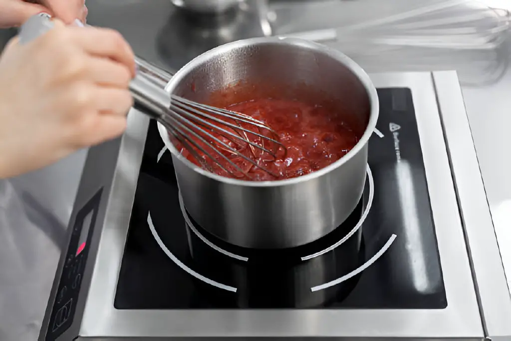 cooks strawberry puree with sugar in a saucepan