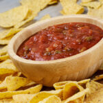 delicious bowl of roasted corn-tortilla-chips on wooden with salsa