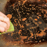 cleaning electric grill dirty plate detail on woman-hand holding wet sponge