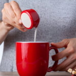 adding creamer into a cup of hot beverage