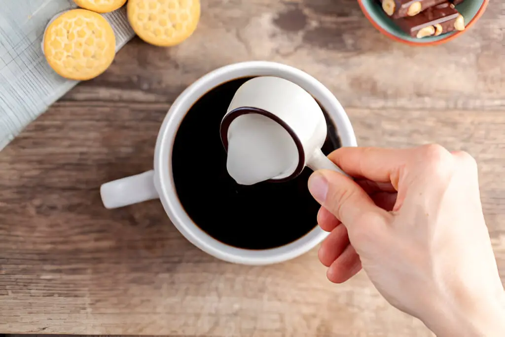 adding creamer into black coffee