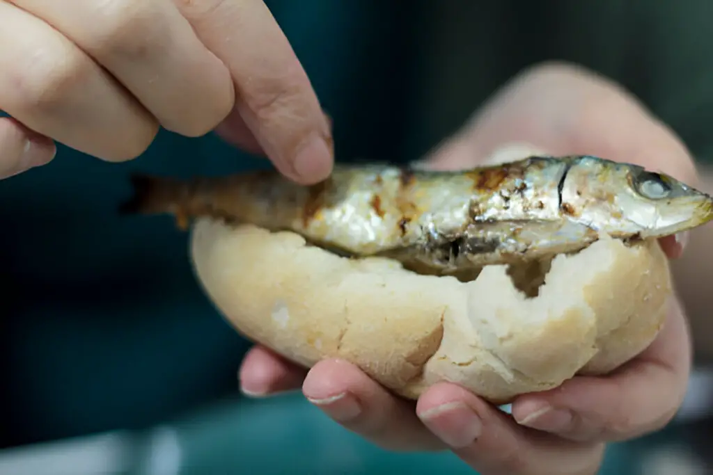 eating roasted sardines with hands