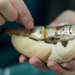 eating roasted sardines with hands