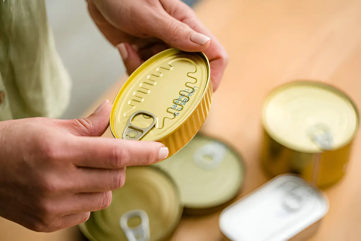 hands holding a tin can showing expiration date