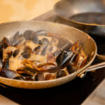 mussels in a cream and white wine sauce are cooked on the stove