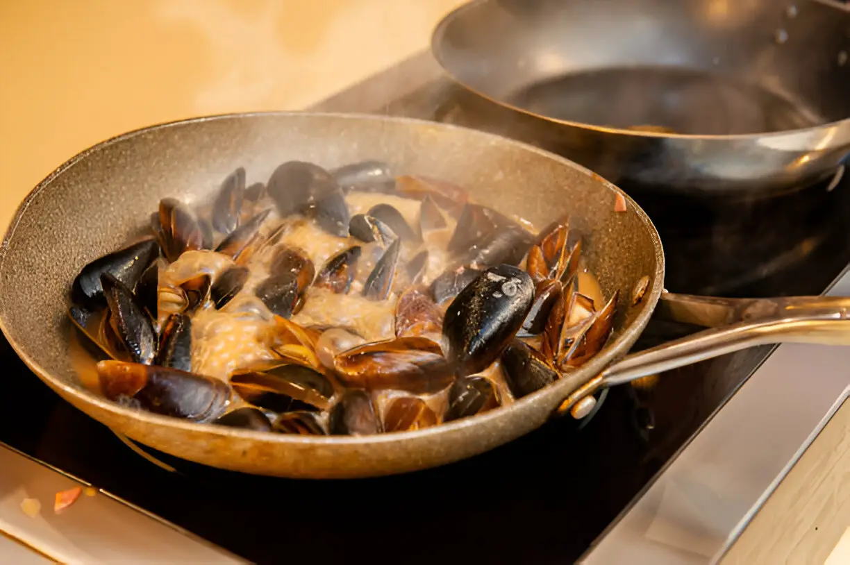 mussels in a cream and white wine sauce are cooked on the stove