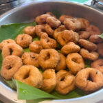 pile of medu vada in open lidded stainless steel catering dish