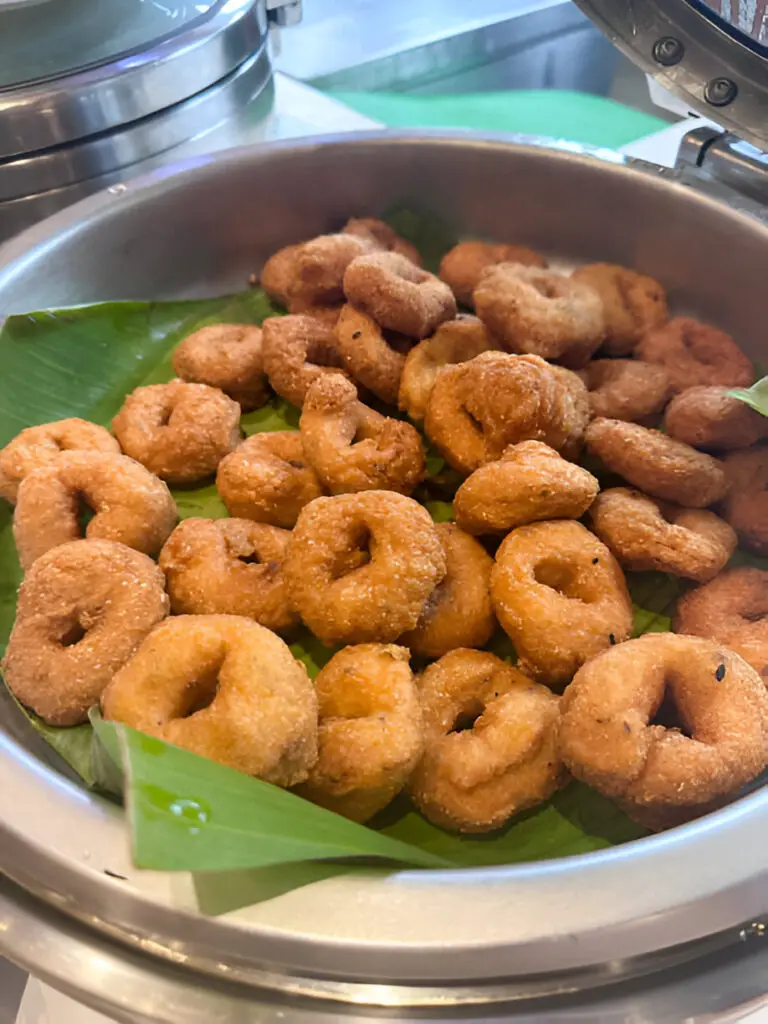 pile of medu vada in open lidded stainless steel catering dish