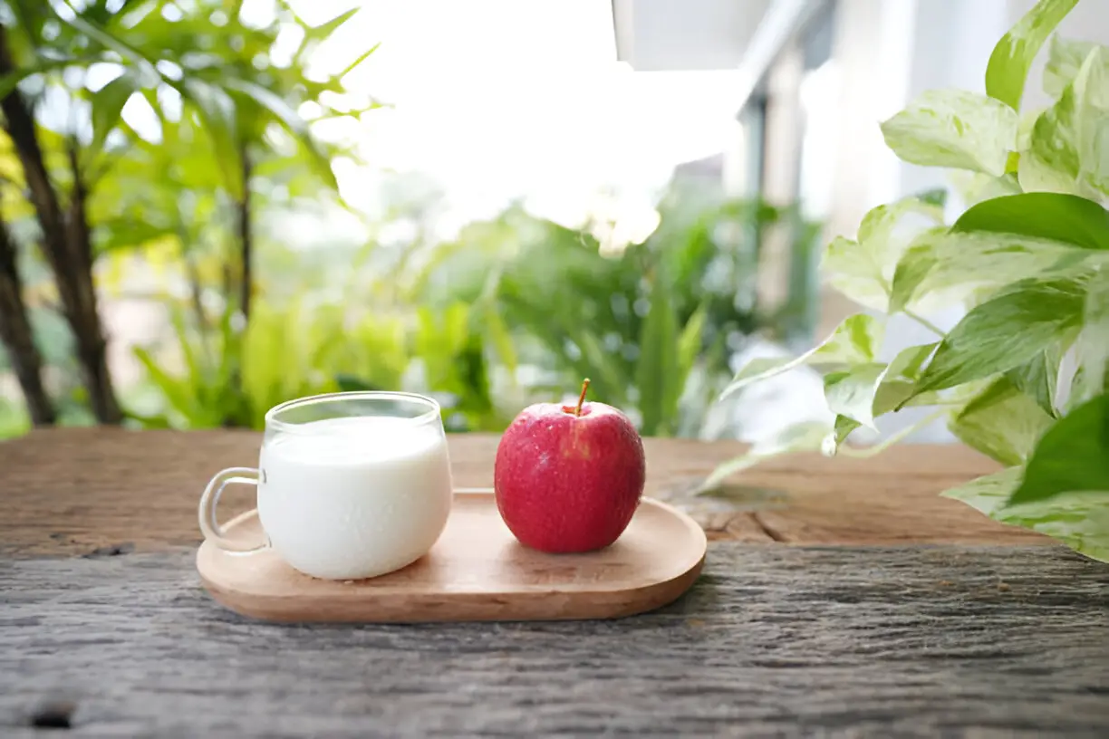 a cup of milk and red apple