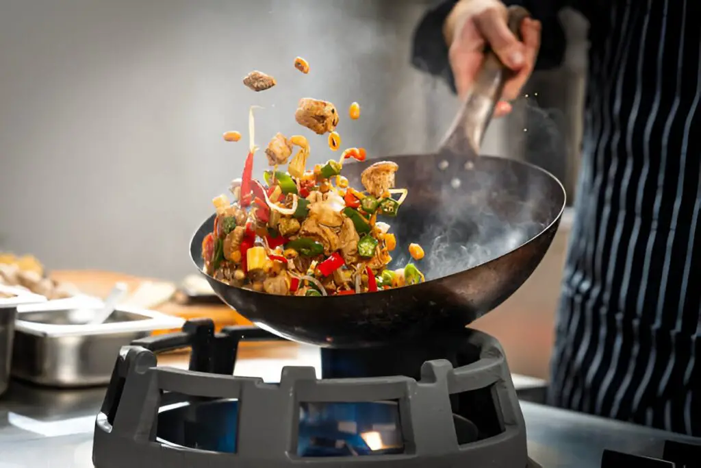 cook stir frying vegetables and meat in a wok
