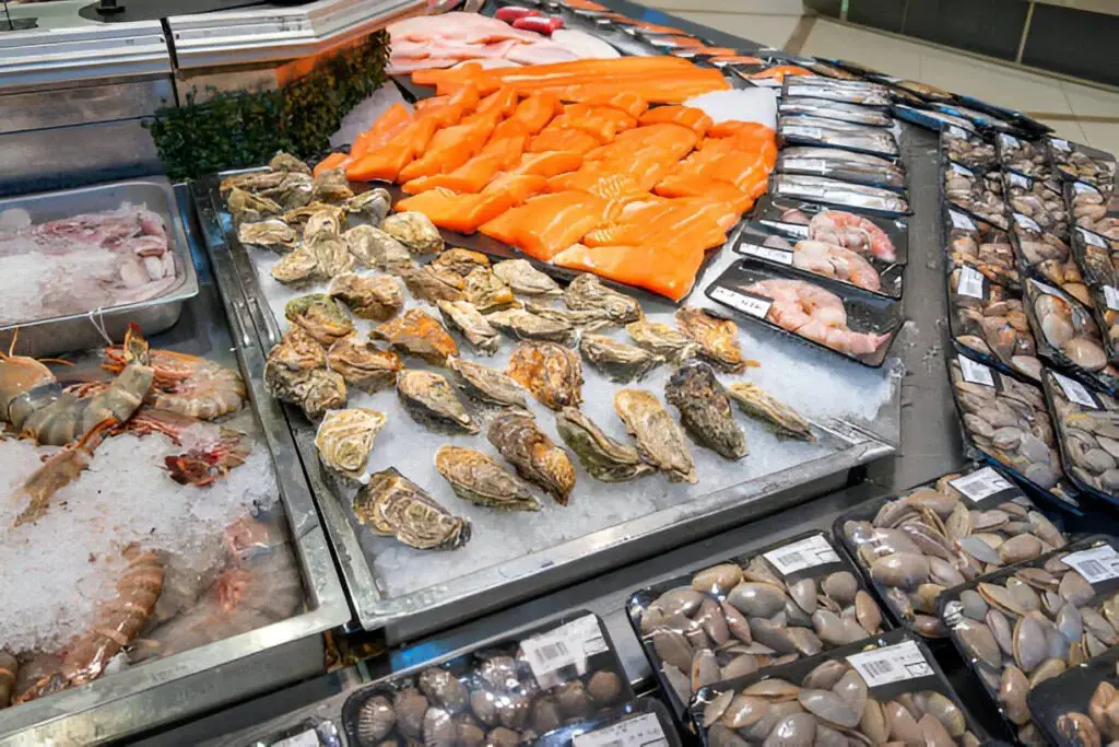 fresh seafood display with various shrimps salmon fillet oysters clams shellfish
