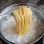 yellow noodles or spaghetti cooking in boiling water