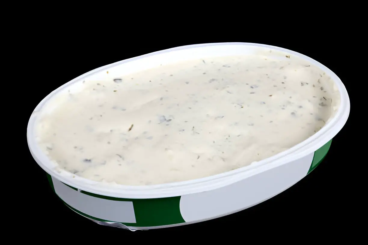 oval open plastic box with soft cheese with garlic and dill isolated