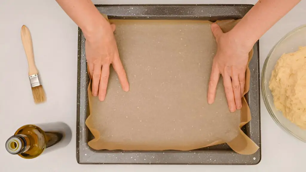 placing parchment paper onto-baking-pan-step-by-step-homemade pizza recipe baking