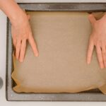 placing parchment paper onto-baking-pan-step-by-step-homemade pizza recipe baking