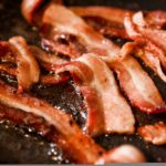 sizzling bacon frying in a pan