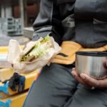 worker holding cup with hot tea and sandwich