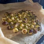 oven roasted brussel sprouts on beige baking paper in metal sheet
