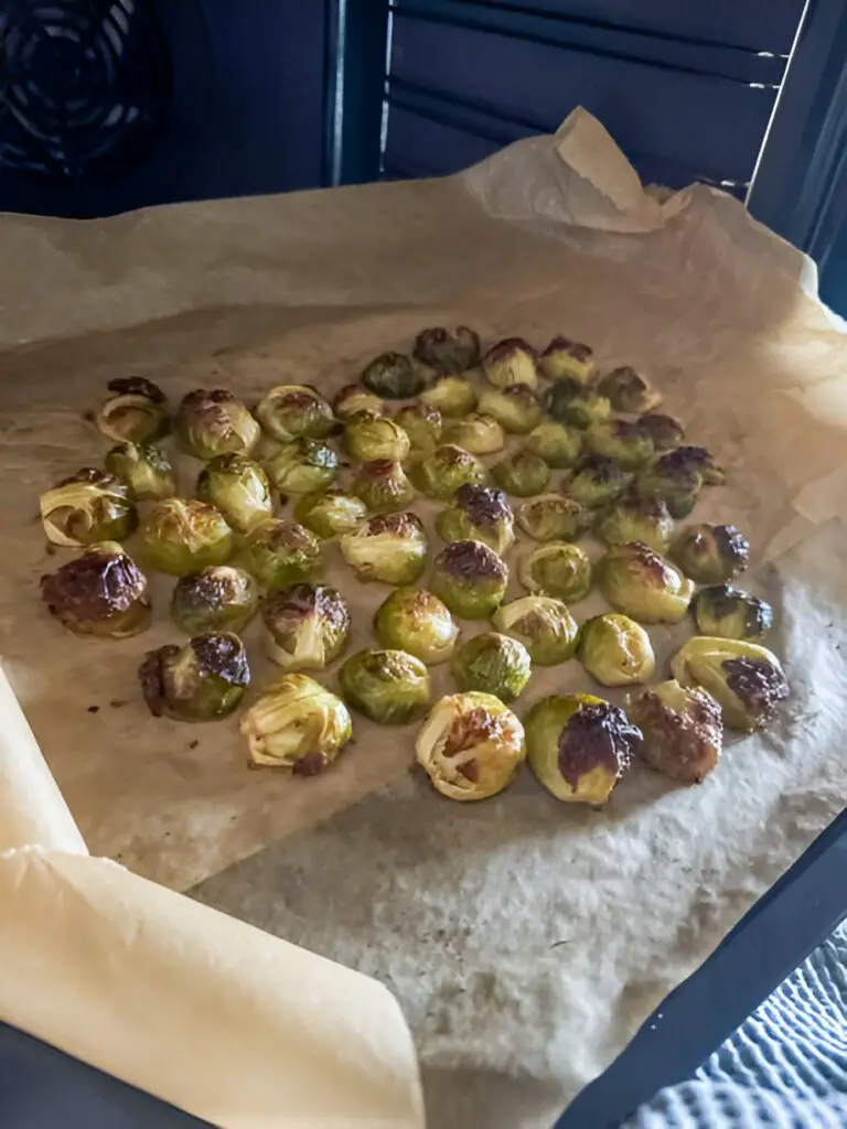 oven roasted brussel sprouts on beige baking paper in metal sheet
